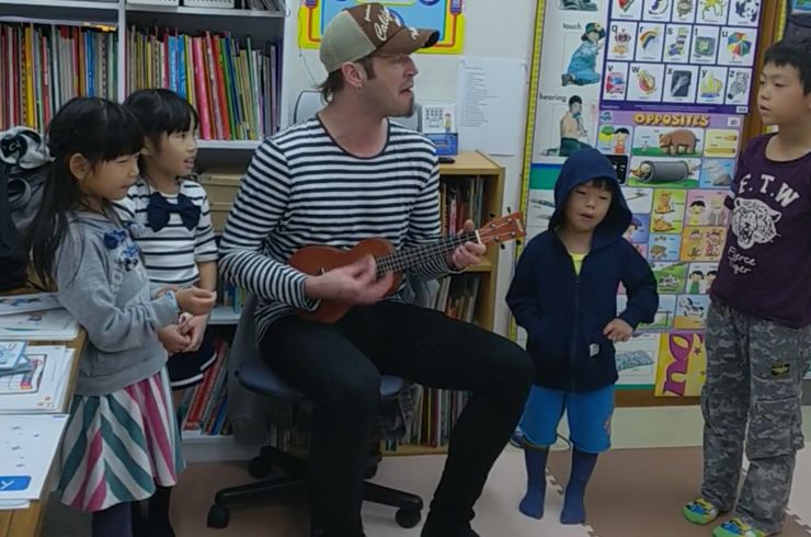 外国人講師と子どもたちが一緒に歌っている
