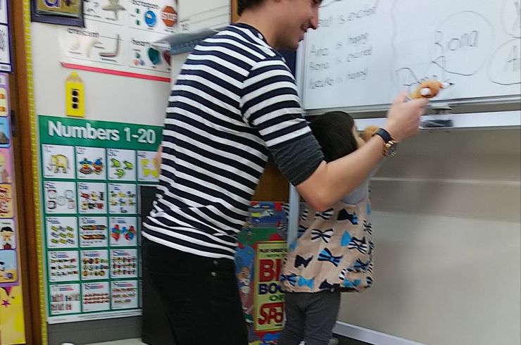 外国人講師と子どもがホワイトボードに字を書いている