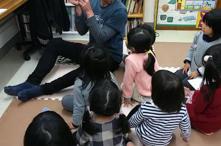 子どもたちが先生の絵本を見つめている